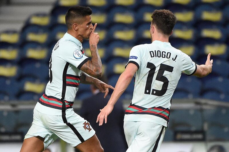 Portugal's defender Joao Cancelo (L) celebrates with Portugal's forward Diogo Jota after scoring a goal during the UEFA Nations League A group 3 football match between Portugal and Croatia at the Dragao Stadium in Porto on September 5, 2020. (Photo by MIGUEL RIOPA / AFP)