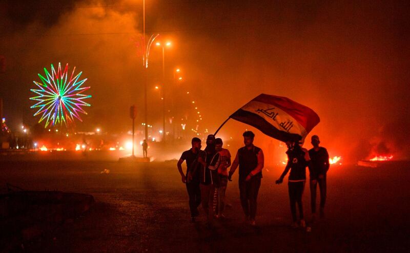 Protesters wave the Iraqi national flag at a roadblock in the southern city of Basra. AFP