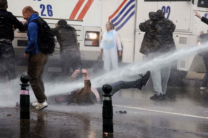 A demonstrator is knocked down by a water cannon during clashes with riot police at the Bois de La Cambre park in Brussels,  Belgium, during a protest against Covid-19 restrictions.  AFP