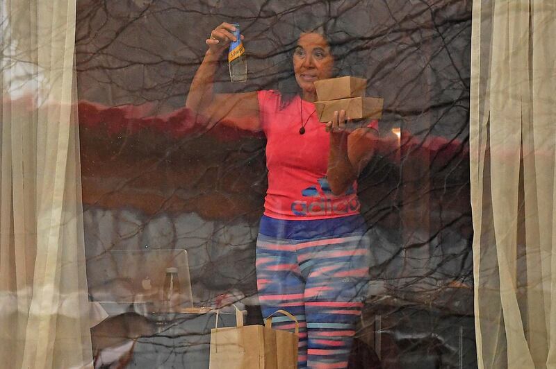 A woman holds boxes and a bottled drink in her room at the Radisson Blu hotel at Heathrow Airport, where travellers are undertaking mandatory hotel quarantine. AFP