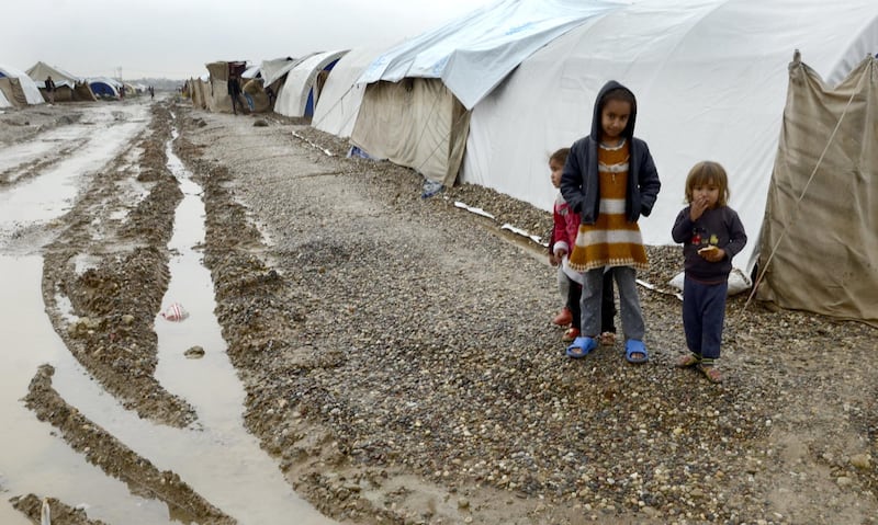 Iraqi displaced children stand at a flooded refugees camp following heavy rainfall in Nimrud town, northeast of Mosul city, northern Iraq, after nearly 600 refugee tents were destroyed. AFP
