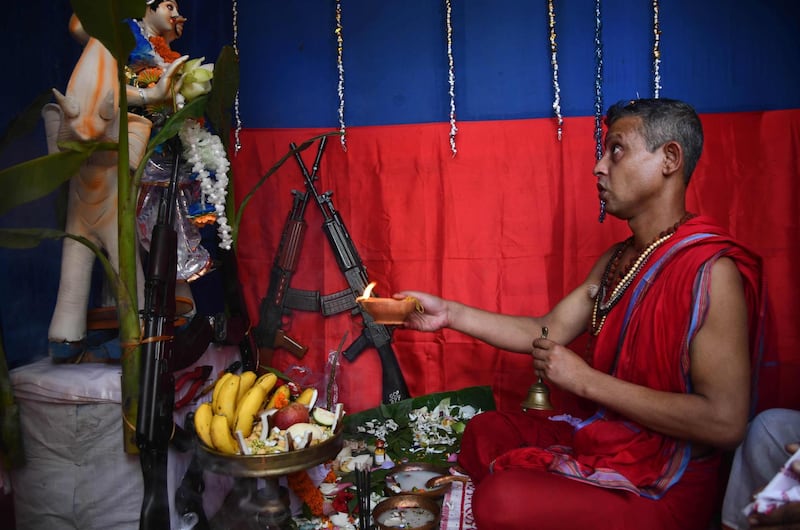 A Hindu priest performing rituals as he offers prayers to a clay idol of the Hindu deity Vishwakarma and weapons belonging to Assam state police during the Vishwakarma Puja festival in Guwahati. Vishwakarma Puja is celebrated to worship Vishwakarma and for people to worship their tools and machinery in his name. Biju Boro/AFP