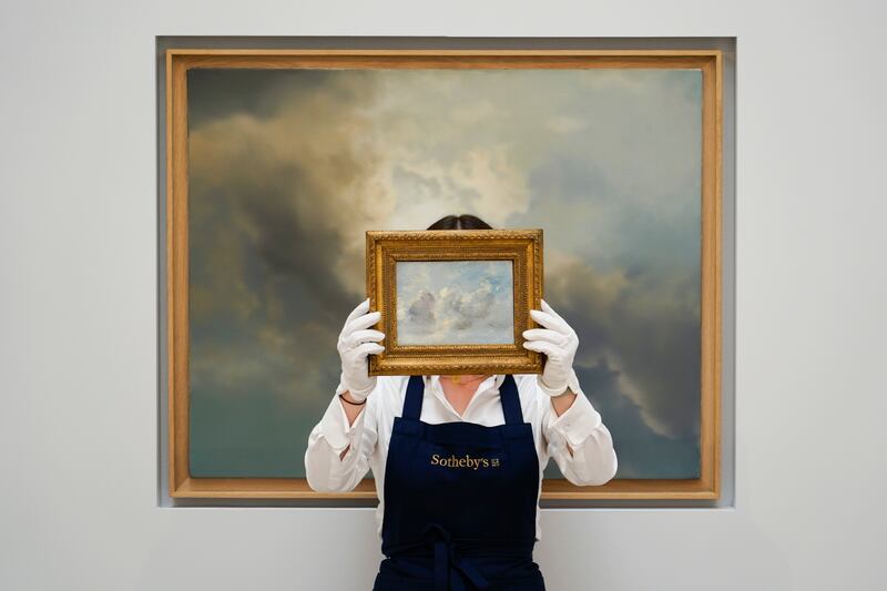 A member of the staff holds the painting 'Cloud Study' by John Constable, against the backdrop of 'Study for Clouds' by Gerhard Richter at Sotheby's in London. The piece has an estimated price of £100,000 to £150,000, while 'Study for Clouds' is £6 million to £8million and will go to auction on June 29. AP