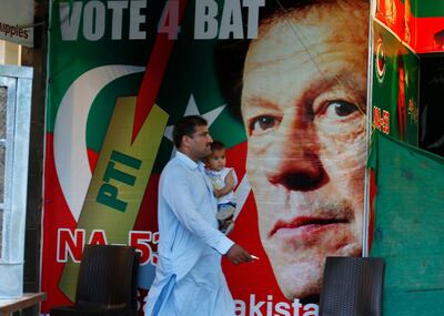 A Pakistani walks past a poster of Imran Khan, head of Pakistan Tehreek-e-Insaf party, at a market in Islamabad, Pakistan, Saturday, July 28, 2018. The party of cricket star Imran Khan says it has acquired the support of the lawmakers required to form a coalition government after winning this week's polls. (AP Photo/Anjum Naveed)