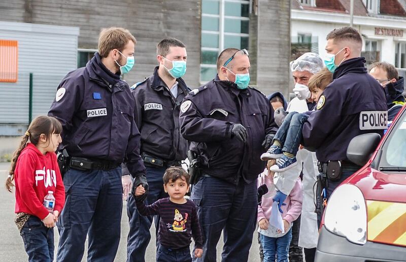 French Gendarmes and police, wearing protective masks against the noverl coronavirus, COVID-19, assist migrants, including five children and a baby, who tried to reach England by crossing the Channel, and who were rescued off the French port city of Calais on May 16, 2020.  French maritime authorities said they picked up 16 migrants, including one child, in the English Channel in the early hours of May 16, 2020. The Britain-bound group was rescued some six kilometres 3.8 miles) off the French port of Calais after their makeshift vessel ran into difficulties around 3:30 am (0130 GMT) and called for help, they said.
 / AFP / BERNARD BARRON

