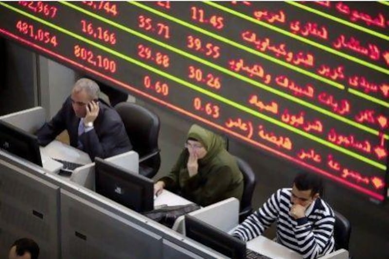 Financial traders work at their desks beneath a screen displaying financial data inside the Egyptian stock exchange in Cairo, Egypt, on Tuesday, Nov. 22, 2011. Egypt's benchmark dollar bonds slumped, sending the yield to the highest level since January, after concessions made by the country's military rulers were rejected by protesters demanding a civilian government. Photographer: Shawn Baldwin/Bloomberg *** Local Caption *** 942908.jpg