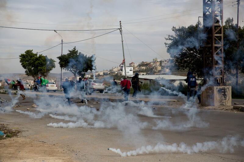 Palestinian demonstrators run from tear gas fired by Israeli troops during clashes after a demonstration against the arrest of members of Fatah in Jerusalem by the Israeli authorities, at Hawara checkpoint near the West Bank city of Nablus. AP
