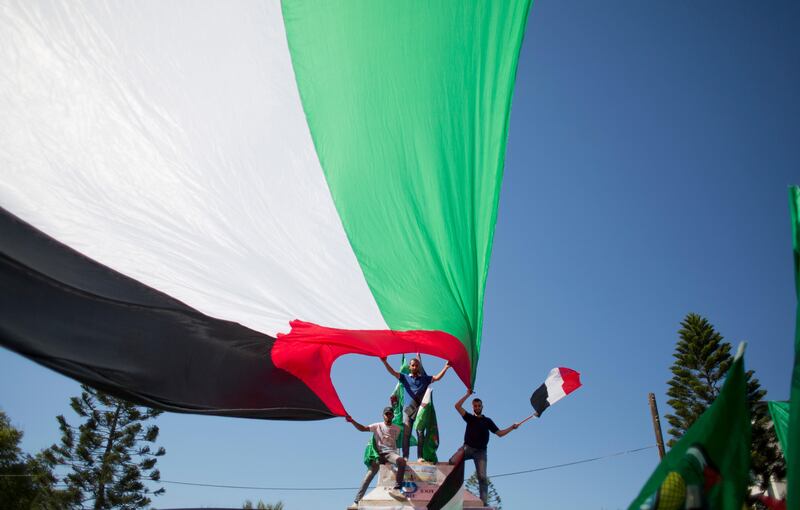 Palestinians waving national and Egyptian flags celebrate the reconciliation agreement between Hamas and Fatah in Egypt, in Gaza City, Thursday, Oct. 12, 2017. The rival Palestinian groups reached a preliminary agreement Thursday that could return the Gaza Strip to President Mahmoud Abbas' control and ease a decade-old Israeli-Egyptian blockade of the coastal territory, but past attempts at unity have foundered on key issues that remain unresolved. (AP Photo/Khalil Hamra)