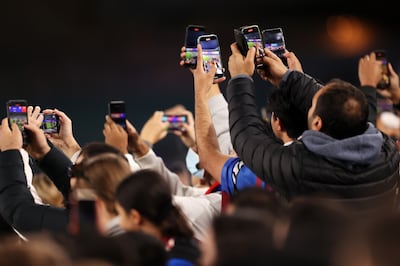 The flash of camera bulbs has been replaced by the glare of mobile phone screens at sporting events. Photo: Getty Images

