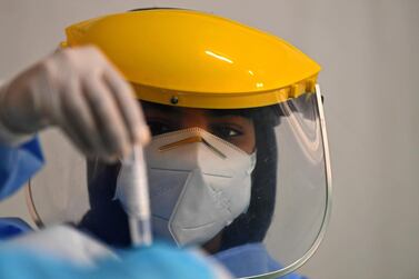 A health worker in the UAE examines a sample to test for Covid-19. AFP