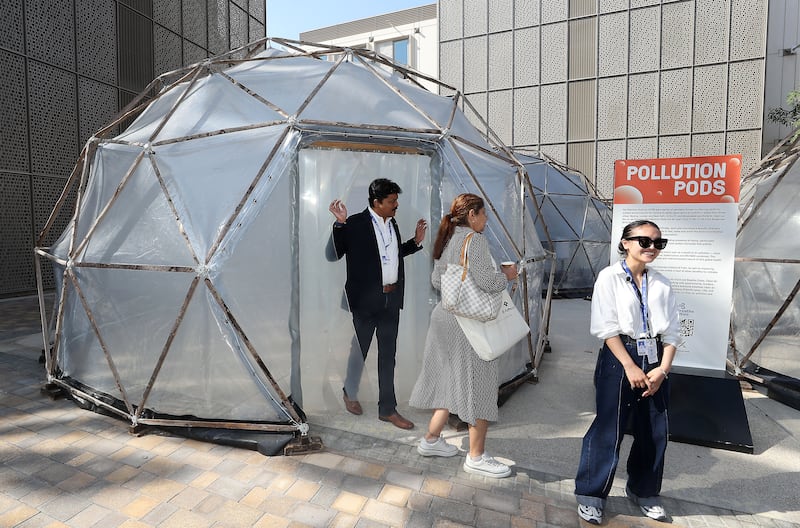 Cop28 attendees visit British artist Michael Pinsky's Pollution Pods, which replicate the air quality in Beijing, London and New Delhi, at Expo City in Dubai. Pawan Singh / The National