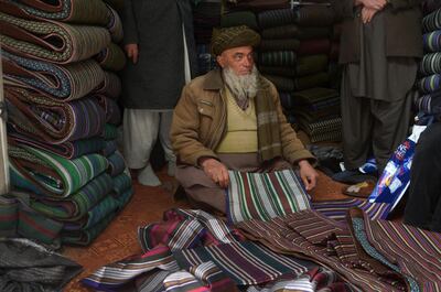 In this photo taken on March 10, 2018, an Afghan shopkeeper and provincial contractor of Zarif Design House shows original fabric to made a chapan (coat) at his shop in Mazar-i-Sharif.
Cheap, Chinese-made nylon burkas are flooding Afghanistan's north as consumers turn to affordable, mass-produced fabrics -- but in Kabul a small, determined fashion house is fighting to preserve the traditional textiles once integral to Afghan culture.
 / AFP PHOTO / FARSHAD USYAN / TO GO WITH Afghanistan-lifestyle-social-fashion,FEATURE by Anne Chaon
