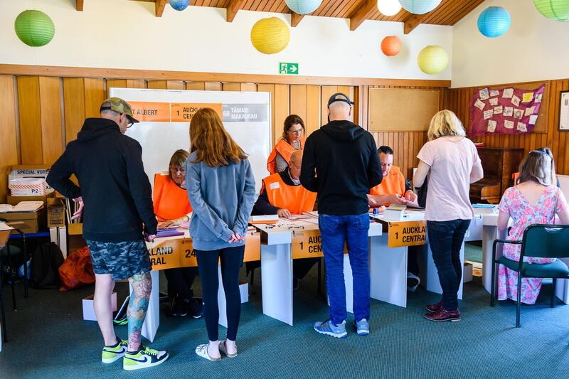Voters receive their ballot papers from election officials at a polling station during the New Zealand General Election in Auckland. Bloomberg