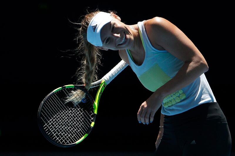 Caroline Wozniacki of Denmark laughs as her hair is caught in the racquet during a practice session before the Australian Open tennis tournament. Edgar Su / Reuters