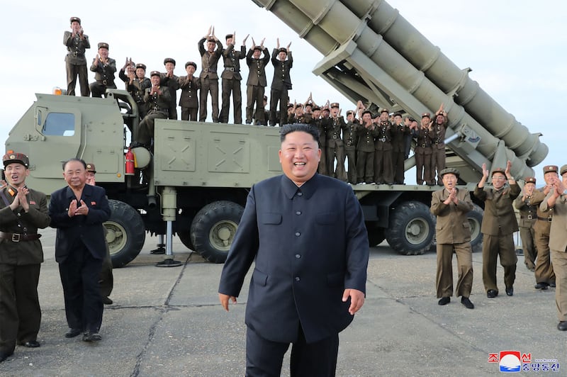 North Korean leader Kim Jong-un celebrating the test-firing of a 'newly developed super-large multiple rocket launcher' at an undisclosed location. AFP