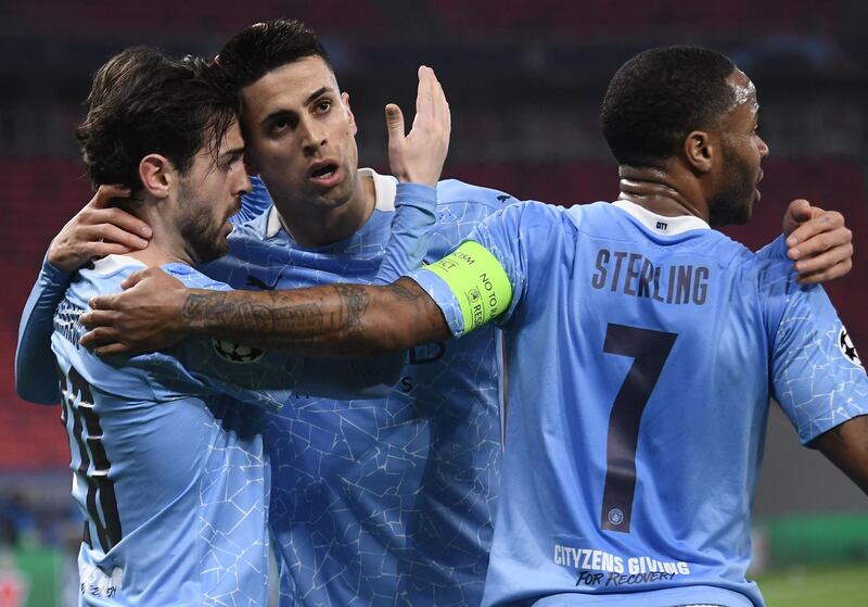 Manchester City's Portuguese midfielder Bernardo Silva (L) celebrates with Manchester City's Portuguese defender Joao Cancelo (C) and Manchester City's English midfielder Raheem Sterling scoring his team's first goal during the UEFA Champions League, last 16, 1st-leg football match Borussia Moenchengladbach v Manchester City at the Puskas Arena in Budapest on February 24, 2021.  / AFP / Attila KISBENEDEK
