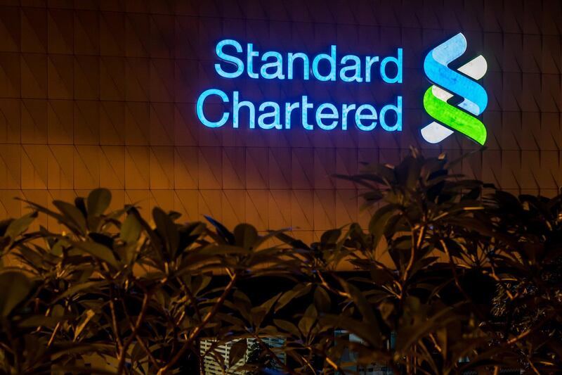 Signage is illuminated atop a Standard Chartered Plc bank branch at night in Hong Kong, China, on Thursday, July 25, 2019. Standard Chartered is scheduled to release interim earnings results on Aug. 1. Photographer: Paul Yeung/Bloomberg