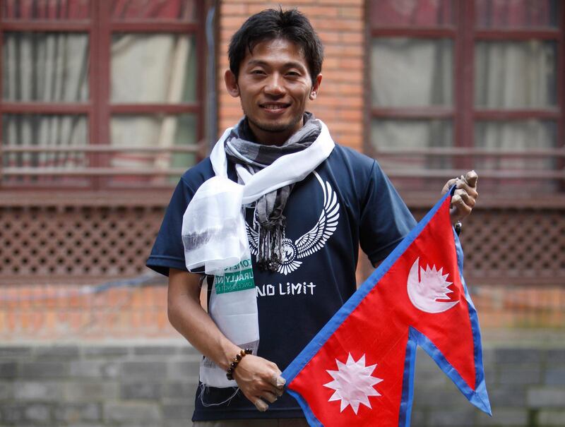 FILE- In this Aug. 23, 2015 file photo, Japanese climber Nobukazu Kuriki poses with a Nepalese flag during a press conference as he attempts to be the first to scale Mount Everest since the April 2015 earthquake that killed 19 mountaineers, in Kathmandu, Nepal. Kuriki and another foreign climber attempting to scale Mount Everest have died on the world's highest peak, a Nepal mountaineering official said Monday, May 21, 2018. (AP Photo/Bikram Rai, File)