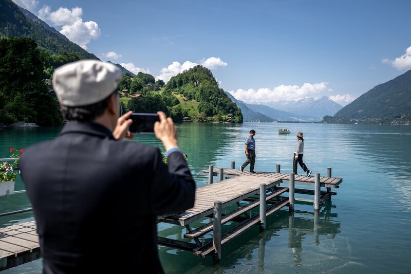 Tourists pose for a photograph on the famous pier of a South Korean Netflix serie in the village of Iseltwald at the shore of Lake Brienz, in the Swiss Alps, on June 2, 2023.  Ever since a hugely popular South Korean series on Netflix featured a romantic scene in this very spot, the picturesque lakeside village of Iseltwald, with a population of around 400 people, has found itself overrun by tourists.  They are fans of "Crash Landing on You", which tells the surreal and unlikely story of a South Korean billionaire heiress who accidentally paraglides into the peninsula's demilitarised zone, crashing into a chivalrous army officer serving North Korean leader Kim Jong Un.  (Photo by Fabrice COFFRINI  /  AFP)