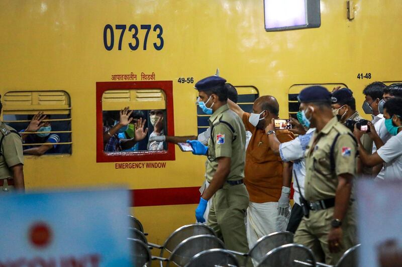 Migrant workers greet Kerala state officials out of the windows as they sit on a train leaving to Odisha at Aluva railway station in Kochi. AFP