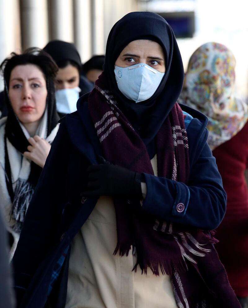 People wearing face masks walk on a sidewalk in downtown Tehran. AP