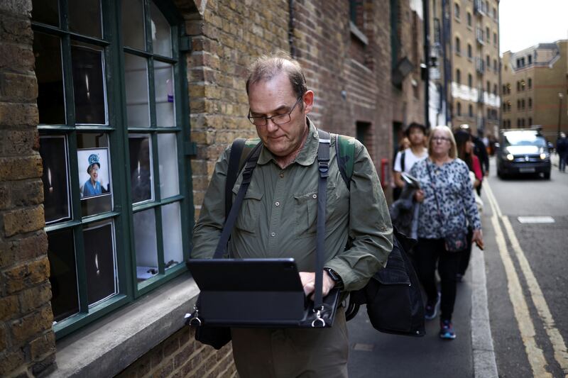 Stuart Murphy works on his iPad as he stands in a queue near Bermondsey, London. Reuters