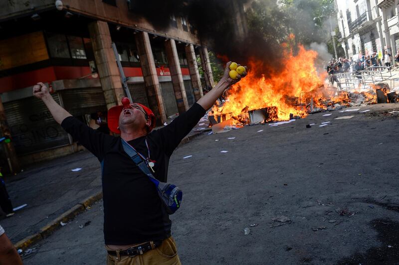 A demonstrator protests in front of a burning barricade during the fifth day of protests against President Sebastian Piñera  in Santiago, Chile.  Getty