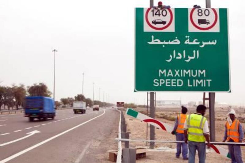 ABU DHABI, UNITED ARAB EMIRATES – April 11, 2011:  Workers hang a sign along E10 posting the new maximum speed limit of 140km an hour.  The new speed limit will begin next Sunday.  ( Andrew Henderson / The National )

