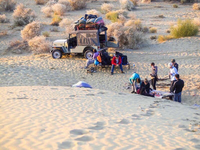 Tourists, man and women at comp place preparing for night in Thar Desert, Rajasthan, India.