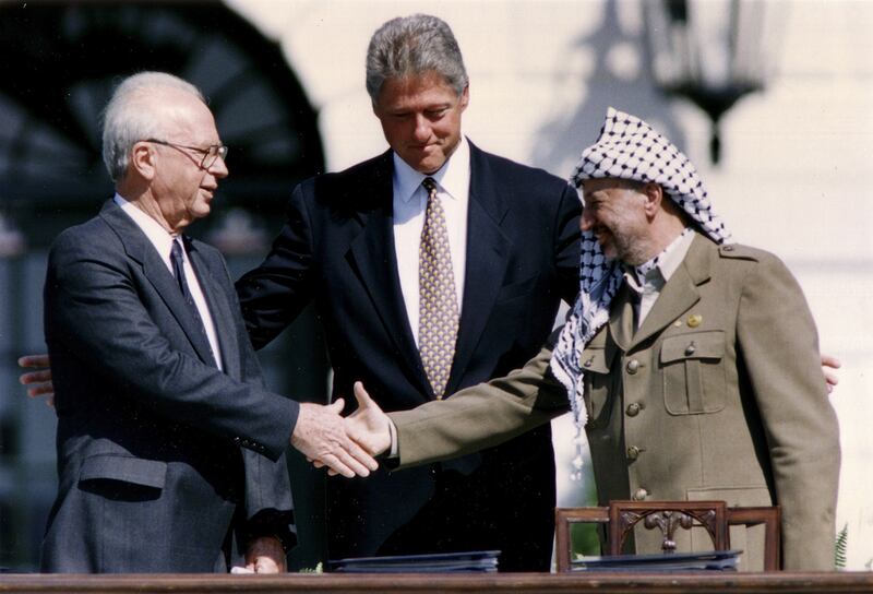 PLO chairman Yasser Arafat  shakes hands with Israeli prime minister Yitzhak Rabin as US president Bill Clinton stands between them, after the signing of the Israeli-PLO peace accord, at the White House on September 13, 1993. Gary Hershorn / Reuters