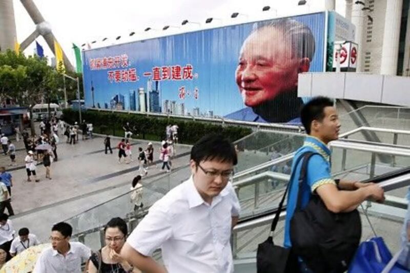 Pedestrians ride an escalator past a poster of Deng Xiaoping, the architect of China's economic reform, in Shanghai in 2010.