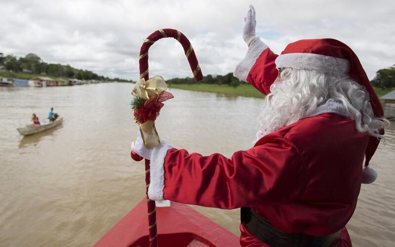 A member of the Amigos do Papai Noel (Friends of Santa Claus) group dressed as Santa Claus waves to residents from a boat during a visit to the community Sao Jose in Careiro da Varzea of Amazonas State, located along the Amazon River banks where the Ribeirinhos (forest dwellers) live. The volunteers of Friends of Santa Claus group have been distributing Christmas gifts to people living in the area since 1998. Bruno Kelly / Reuters