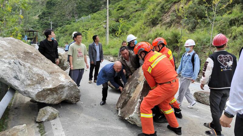 Rescuers and locals remove boulders from the road in Luding county after the quake triggered landslides. EPA