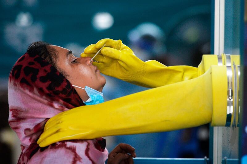 An employee of the Mugda Medical College and Hospital collects a swab sample from a resident to test for the Covid19 coronavirus, in Dhaka, Bangladesh. AFP