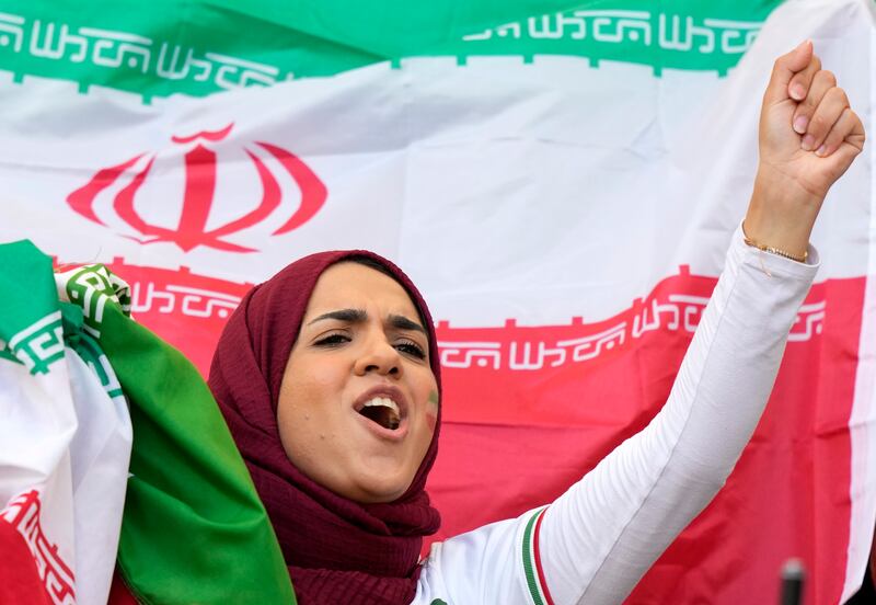 A fan holds Iran's national flag and cheers before the game against England in Doha on Monday. AP