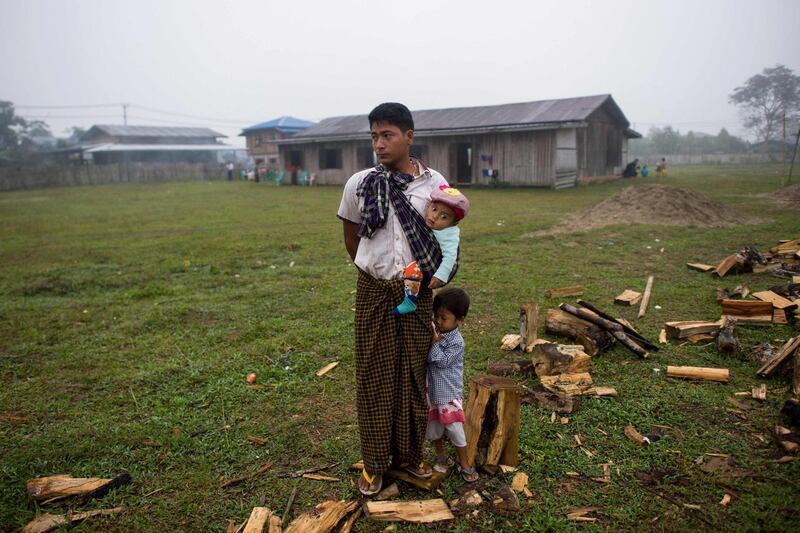 An internally displaced man and his children stand on a field at a temporary shelter in Danai, Kachin state. Thousands of people have fled renewed fighting between Myanmar's army and insurgents in the country's remote north, a United Nations official said, as a long-simmering conflict intensifies. Ye Aung Thu / AFP