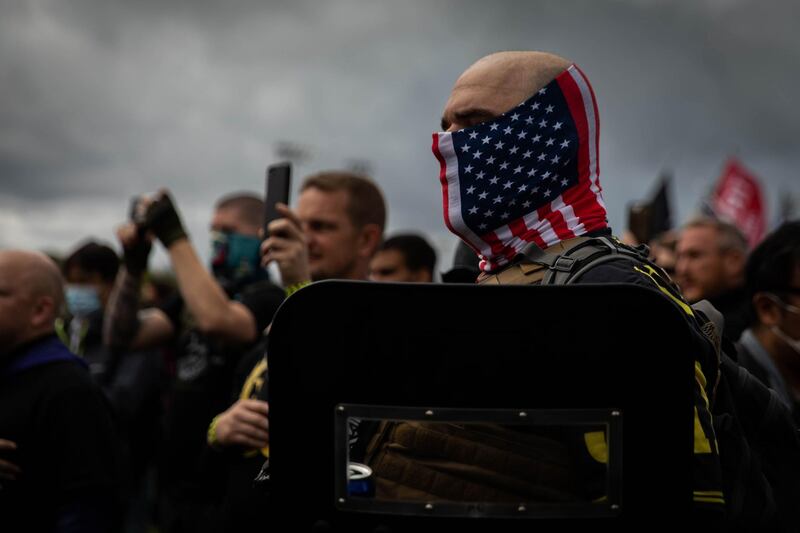 A man hold his hand to his heart as a Proud Boys organizer recites the Pledge of Allegiance during a Proud Boys rally at Delta Park in Portland, Oregon on September 26, 2020. Far-right group "Proud Boys" members gather in Portland to show support to US president Donald Trump and to condemn violence that have been occurring for more than three months during "Black Lives Matter" and "Antifa" protests. 
 / AFP / Maranie R. STAAB
