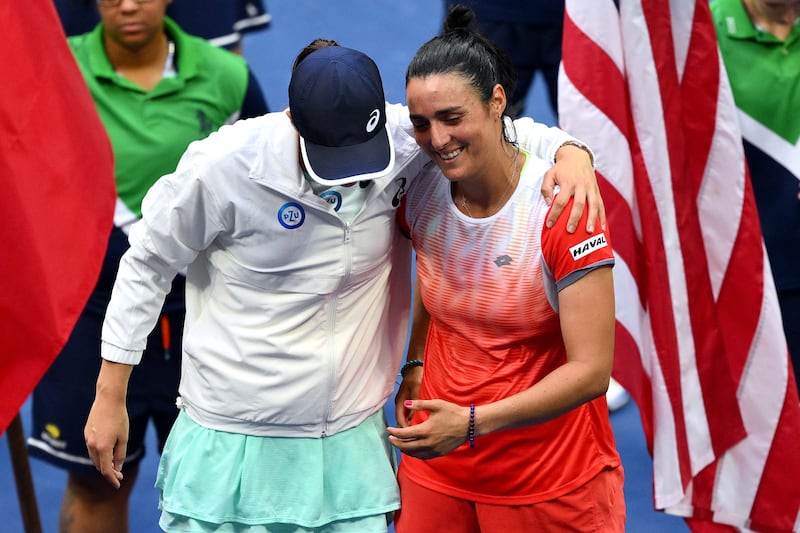 Iga Swiatek hugs Ons Jabeur during the trophy ceremony following the 2022 US Open final. AFP