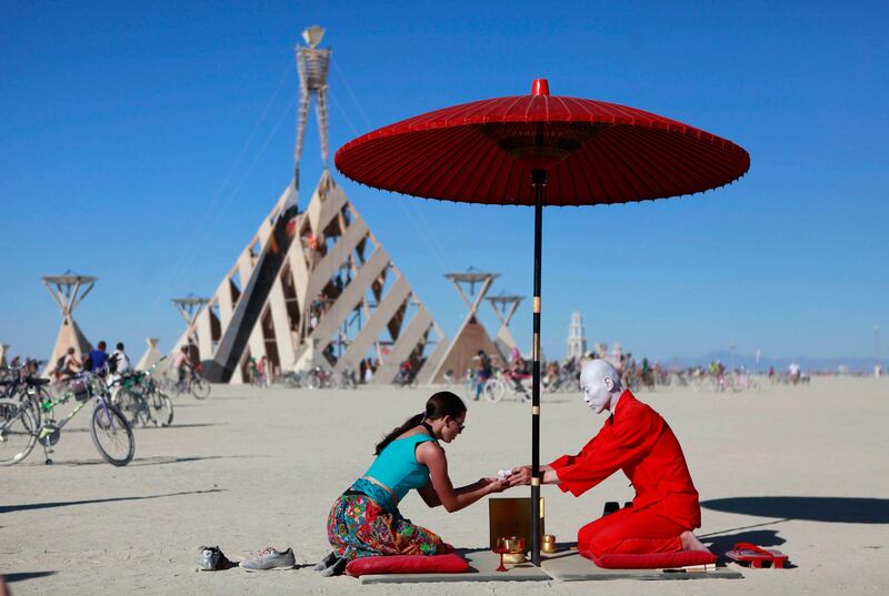 Shaza Anderson (L), takes part in a tea ceremony with Ken Hamazaki during the Burning Man 2011 "Rites of Passage" arts and music festival in the Black Rock desert of Nevada, September 2, 2011. More than 50,000 people from all over the world have gathered at the sold out festival which is celebrating its 25th year.      REUTERS/Jim Urquhart  (UNITED STATES - Tags: SOCIETY ENTERTAINMENT TPX IMAGES OF THE DAY) FOR EDITORIAL USE ONLY. NOT FOR SALE FOR MARKETING OR ADVERTISING CAMPAIGNS. NO THIRD PARTY SALES. NOT FOR USE BY REUTERS THIRD PARTY DISTRIBUTORS *** Local Caption ***  SLC05_USA-_0903_11.JPG