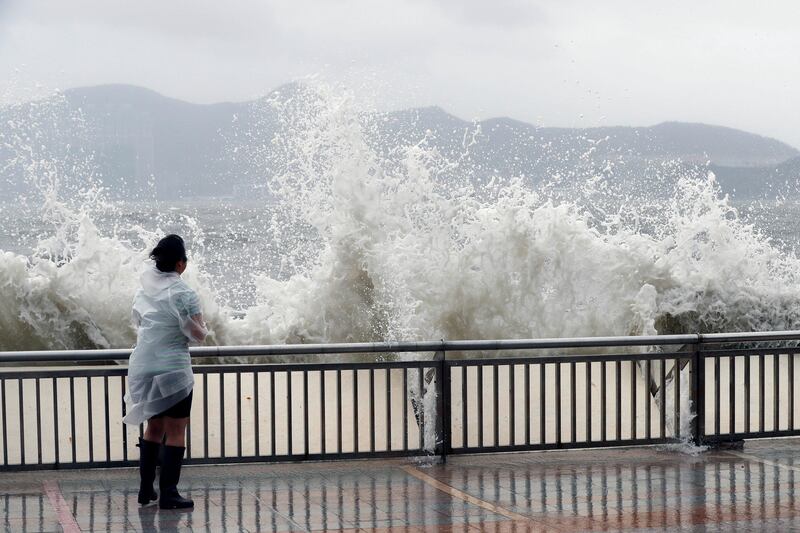 A woman stands beside a big wave on a waterfront Typhoon Hato hitting in Hong Kong, China August 23, 2017. REUTERS/Tyrone Siu