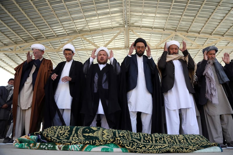 Afghan people offer funeral prayers behind the body of a civilian killed in Sunday's deadly suicide attack at a voter registration center, in Kabul, Afghanistan, Monday, April 23, 2018. Taliban attacks in western Afghanistan killed 14 soldiers and policemen on Monday as residents in the capital, Kabul, prepared for the funerals of those killed in the horrific bombing by the Islamic State group on a voter registration center that left at least 57 dead the previous day. (AP Photo/Rahmat Gul)