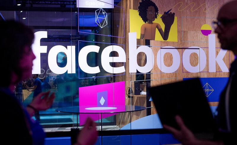 FILE - In this Tuesday, April 18, 2017, file photo, conference workers speak in front of a demo booth at Facebook's annual F8 developer conference, in San Jose, Calif. The chairman of the U.K. Parliament��������s media committee says the government office that investigated the Cambridge Analytica scandal has fined Facebook 500,000 pounds ($663,000) for failing to safeguard users�������� data. (AP Photo/Noah Berger, File)