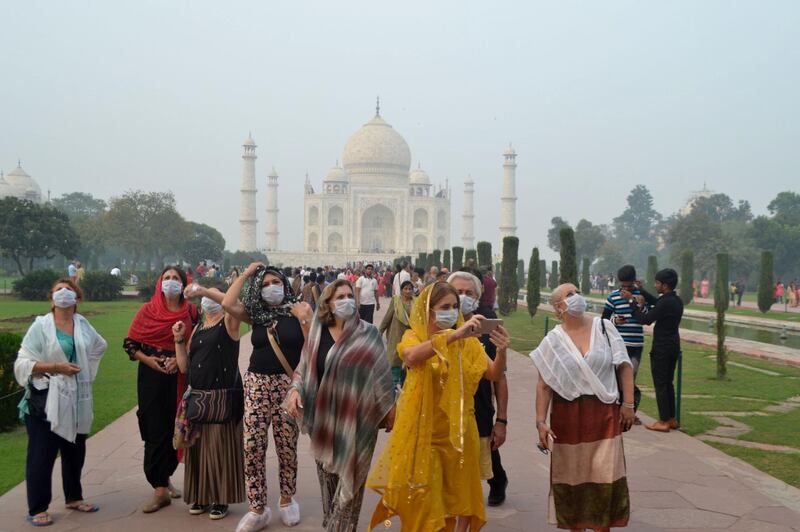 TOPSHOT - Foreign tourists wearing face masks visit the Taj Mahal under heavy smog conditions, in Agra on November 4, 2019. As smog levels exceeded those of Beijing by more than three times, authorities also parked a van with an air purifier near the Taj Mahal -- the iconic 17th-century marble mausoleum 250 kilometres (150 miles) south of Delhi -- in a bid to clean the air in its surrounds, the Press Trust of India reported. / AFP / Pawan Sharma
