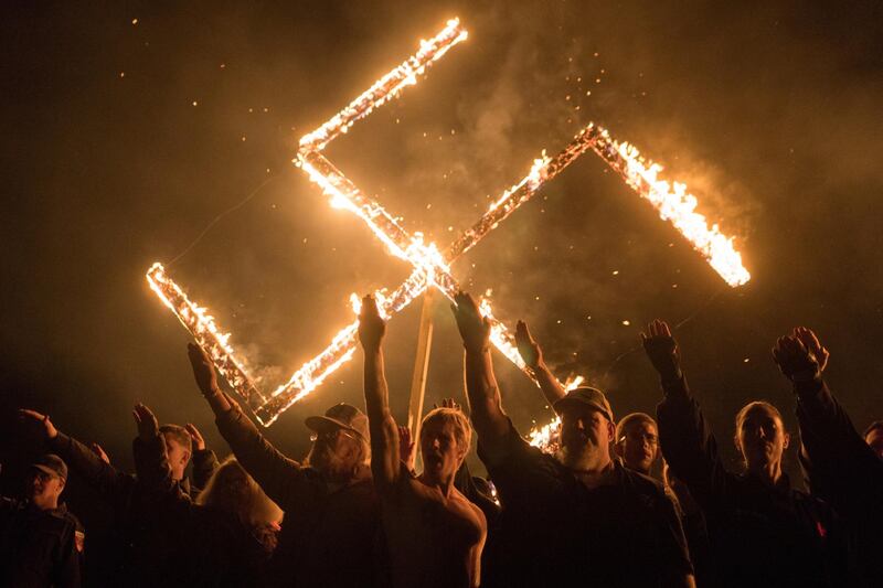 Supporters of the National Socialist Movement, a white nationalist political group, give Nazi salutes while taking part in a swastika burning at an undisclosed location in Georgia, on April 21, 2018. Reuters