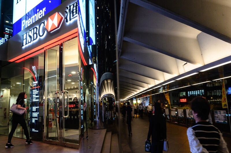 In this picture taken on October 25, a woman (L) walks towards a HSBC branch in Central district in Hong Kong. HSBC pre-tax profits slip 18 percent to 4.8 billion USD in third quarter, the company announced on October 28, 2019. / AFP / Philip FONG
