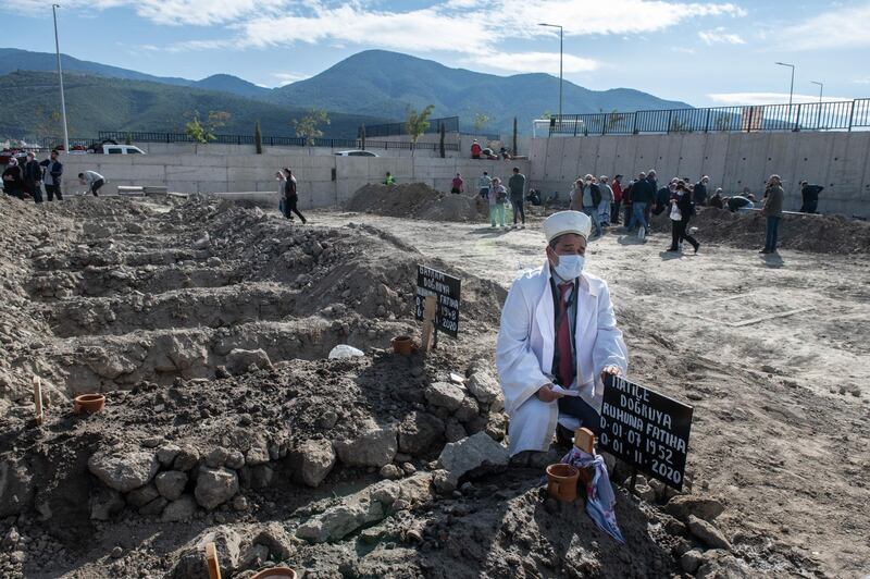 An imam prays near the graves of two members of the Dogruya family who died when a powerful earthquake. Getty Images