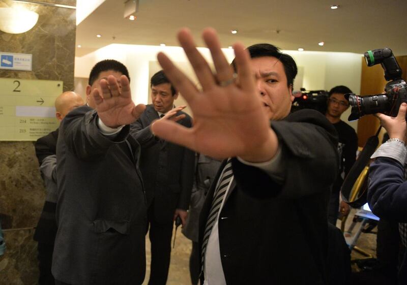 Chinese security guards block photos of a man trying to hand out leaflets to journalists with his theory about the missing Malaysia Airlines flight MH370 at a hotel in Beijing. At their first meeting, Chinese relatives of the missing passengers accused Malaysian officials of wasting time. Mark Ralston / AFP / March 21, 2014.