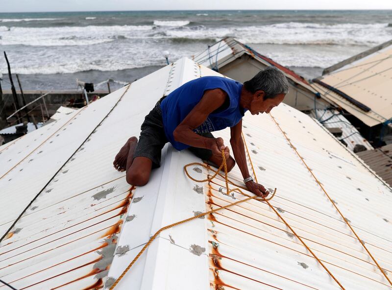 A Filipino secures the roof of a house in Aparri, Cagayan province, Philippines. Francis R Malasig / EPA