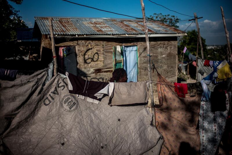 A resident stands behind a fence made of tarp from the U.S. Agency for International Development (USAID) at the Caradeux refugee camp, set up after the 2010 earthquake, in Port-Au-Prince, Haiti, on Tuesday, Jan. 30, 2018. Billions of aid poured in from donors in the years that followed the 2010 earthquake. Yet, the money has done little to address poverty. Haiti President Moise has aimed his strongest criticism at the way foreign aid has been administered in Haiti. Photographer: Alejandro Cegarra/Bloomberg