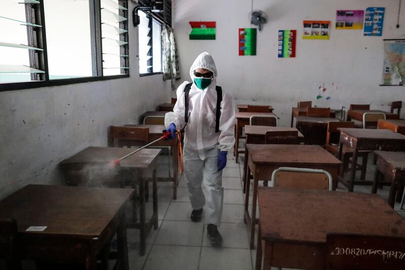 A member of the Indonesian Red Cross wearing a protective suit sprays disinfectant liquid inside a classroom at a school amid an easing of the large-scale coronavirus restrictions in Jakarta, Indonesia. EPA